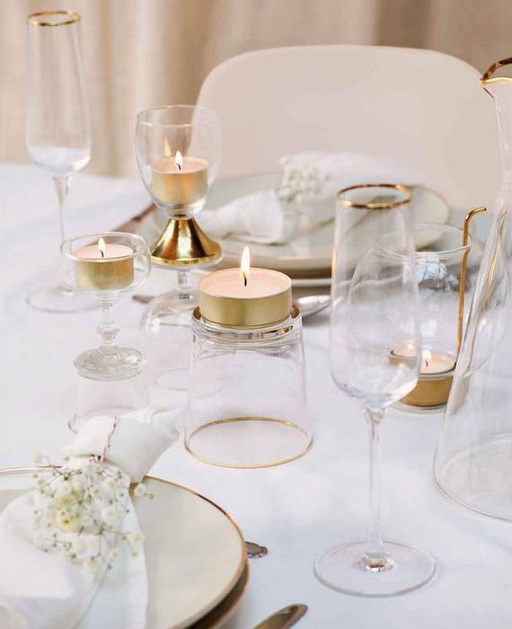 Festlich gedeckte Hochzeitstafel mit weiß-goldenem Geschirr und Gläsern mit Goldrand. Auf und in die Gläser wurden Teelichte und ein Maxi Teelicht im goldenen Alubecher dekoriert.